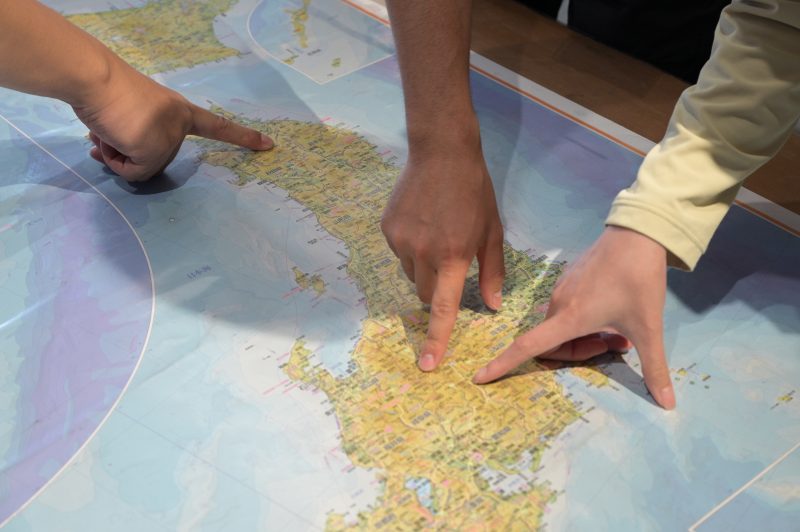 日本地図を囲み、行きたい山について話す様子